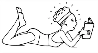 A person is lying on their stomach and reading a book, with their legs bent at the knees. They have curly hair held back with a headband. The person is wearing casual clothing. They appear focused on the book.